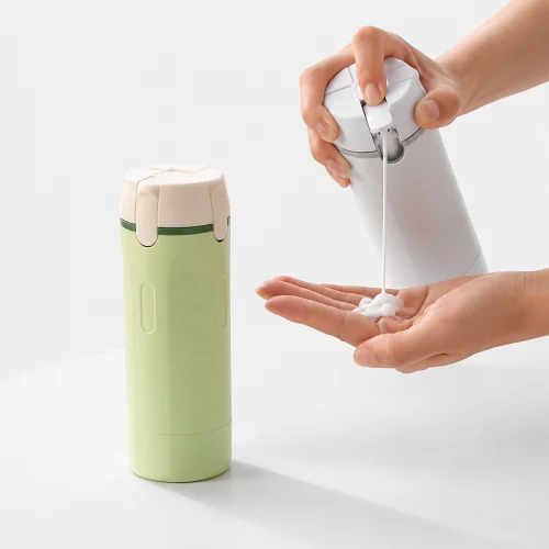 Hand holding the Premium 4-in-1 leak-proof travel toiletry dispenser bottle, showcasing its compact size, refillable design, and portable travel-friendly convenience.