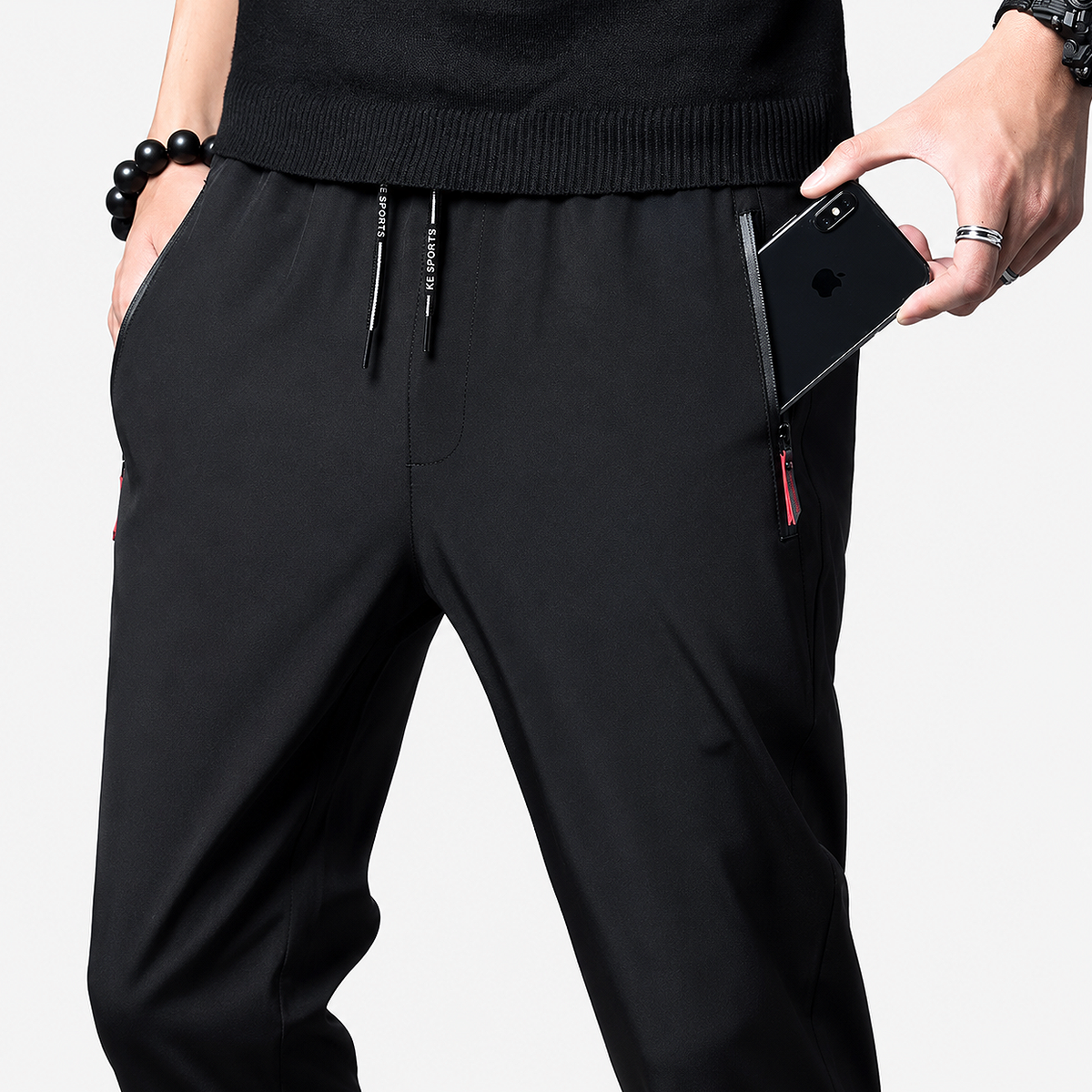Men’s lightweight casual elastic waist trousers in black showing the printed drawstrings and a smartphone in the zipper pocket.