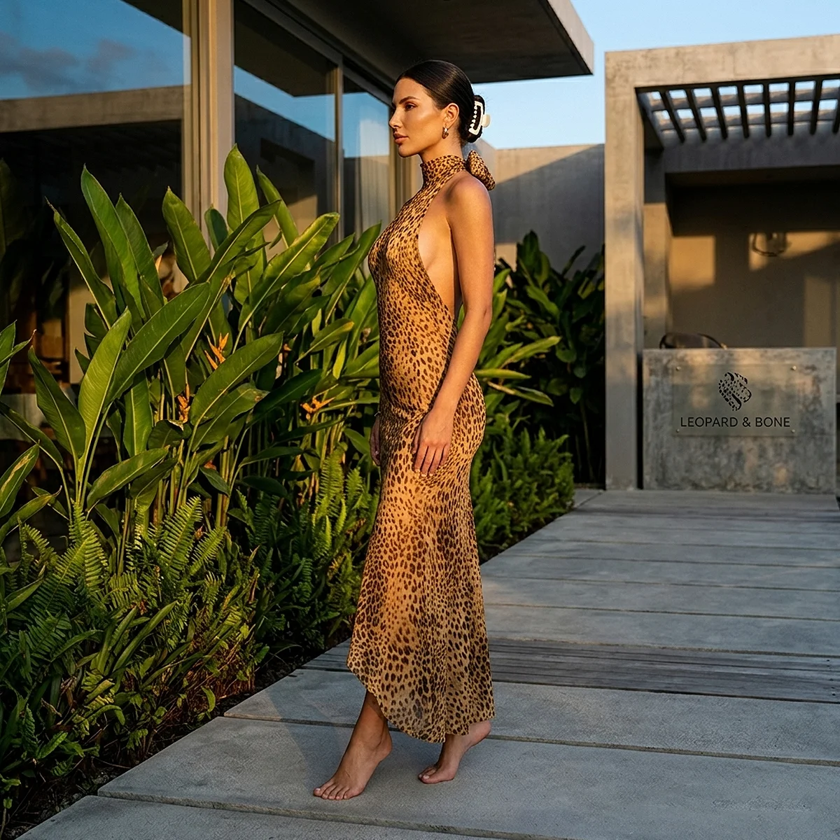 Side profile view of a woman wearing the ACUVICK Leopard Print Halter Neck Bodycon Mini Dress standing on an outdoor walkway